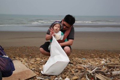 謝姓爸爸背著孩子參加淨灘，表示環保活動應從小扎根(攝影新竹林區管理處彭馨儀)